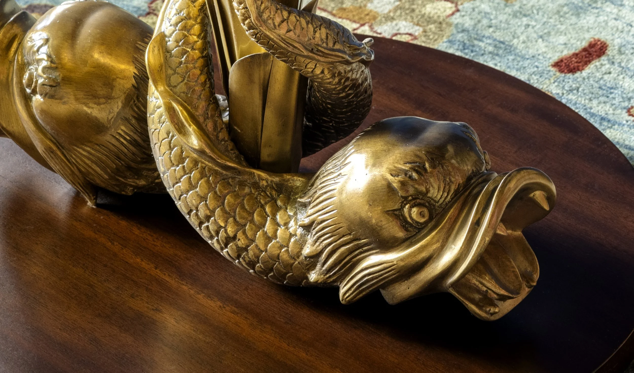 Gold-colored decorative fish sculpture with detailed scales and fins on a wooden surface.