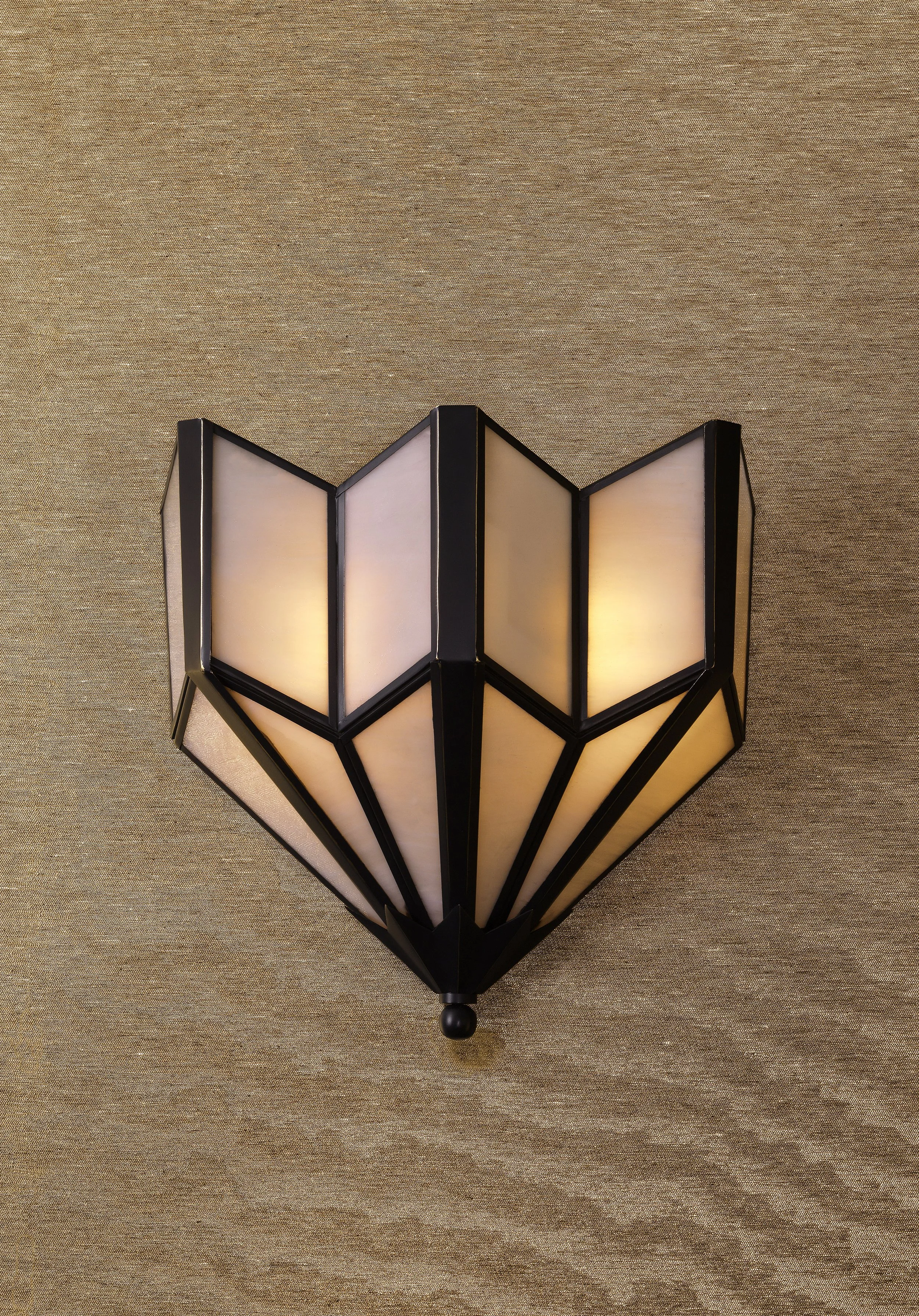 A black and white Asian-style lantern shaped like a blooming flower with multiple panels, mounted on a beige textured wall.