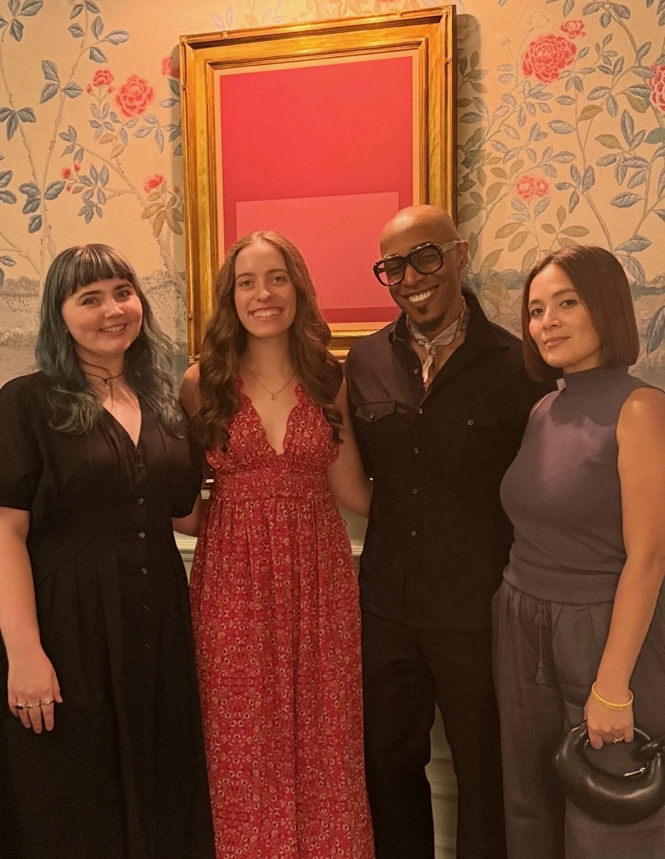Corey Damen Jenkins and his team members in front of floral wallpaper and an abstract pink artwork at the Kips Bay Showhouse dining room.