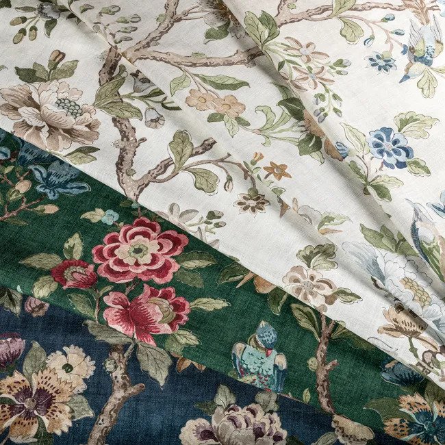 Close-up of layered floral and nature-inspired fabric patterns in white, dark green, and navy blue colors.