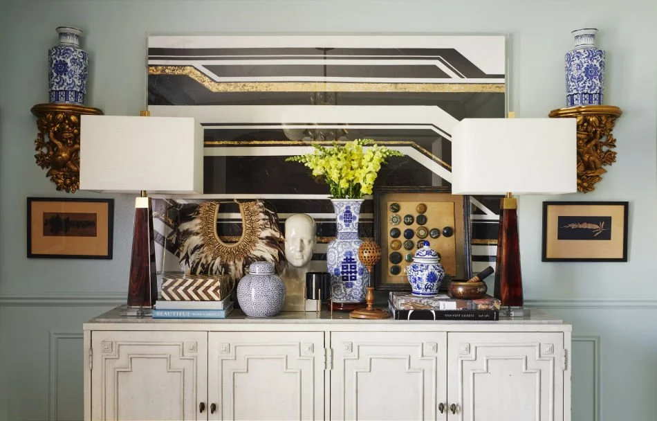 Decorative console table with vases, books, and art pieces in a living room.