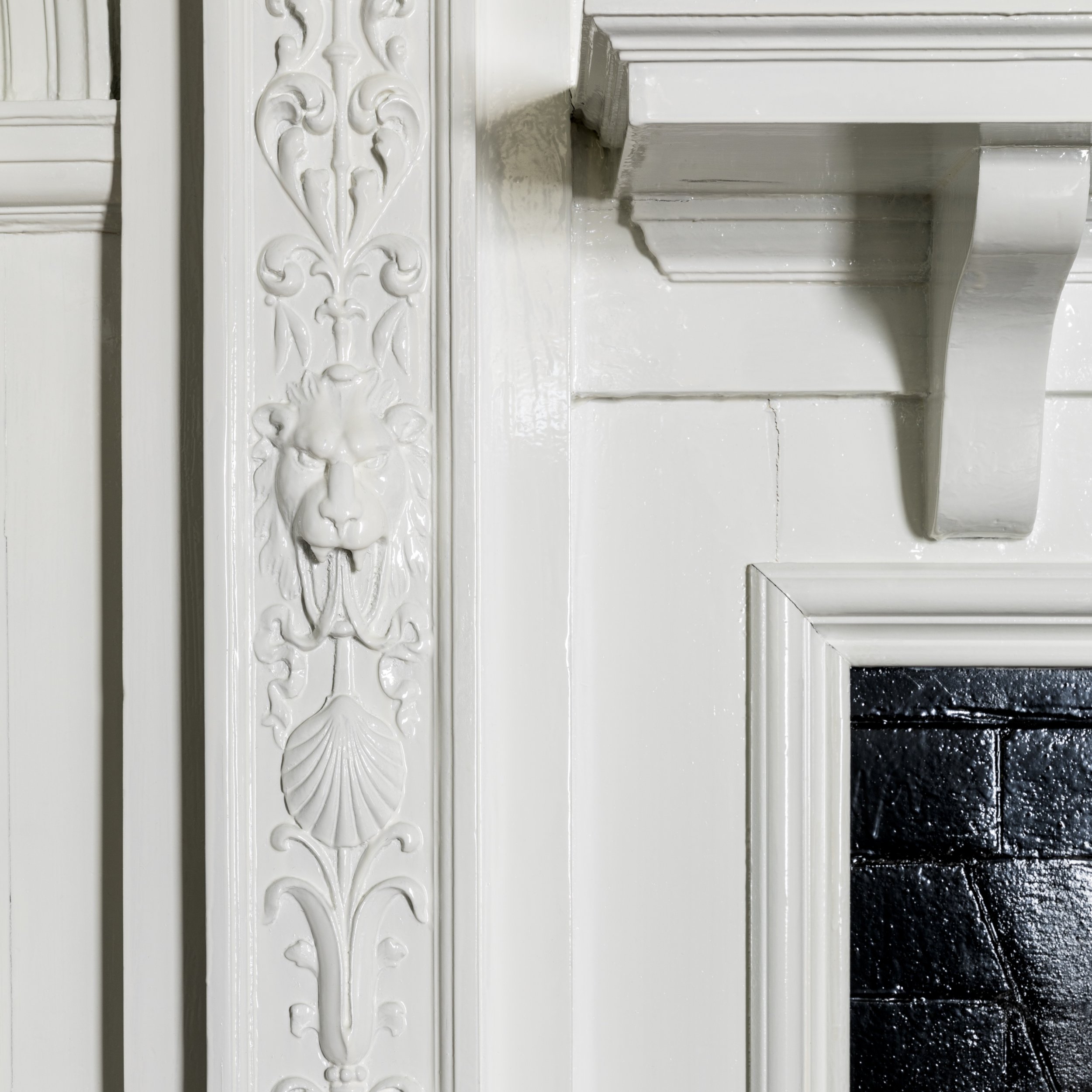 Decorative white fireplace mantel with embossed floral designs and a black granite hearth.