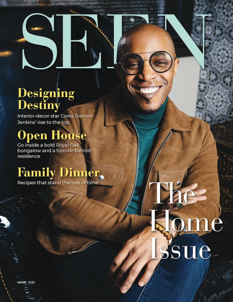 Cover of a magazine featuring a smiling man with glasses, wearing a brown jacket and blue turtleneck, with headlines about home decor, an open house, and family dinner.