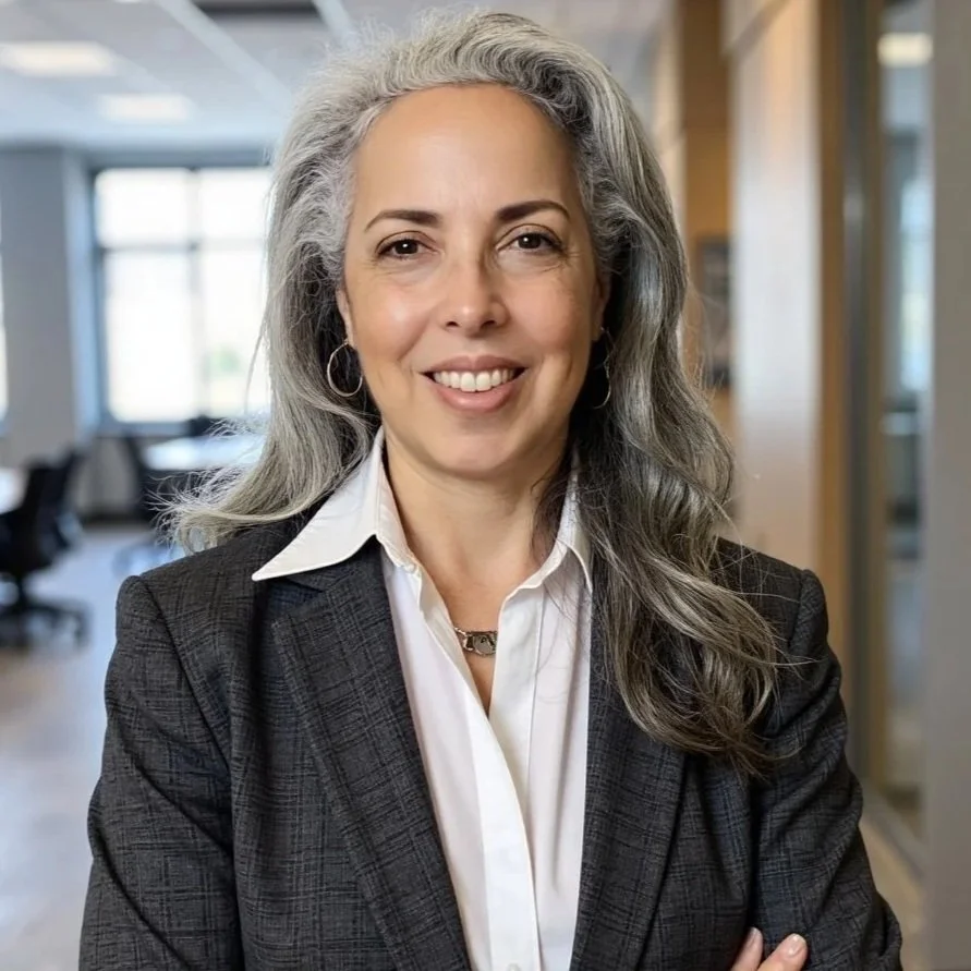 Dr. Lee Cohen wearing a dark blazer over a white shirt, standing in an office environment.