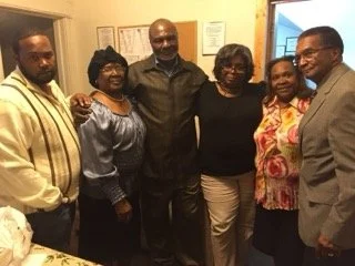 Six people standing together in a room, smiling and posing for a photo.
