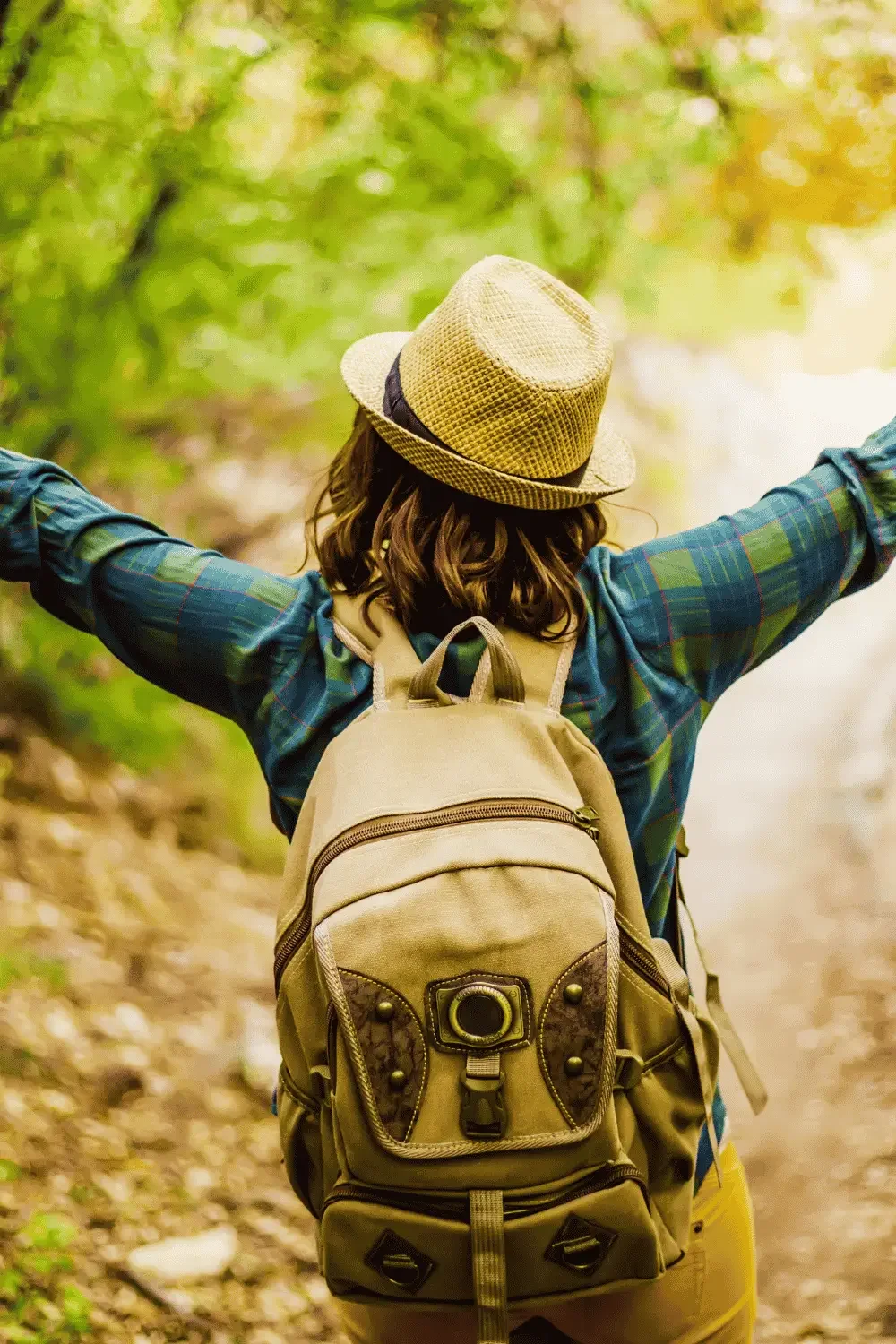 A woman with arms outstretched on a hiking trail, reflecting peace and deep emotional release.