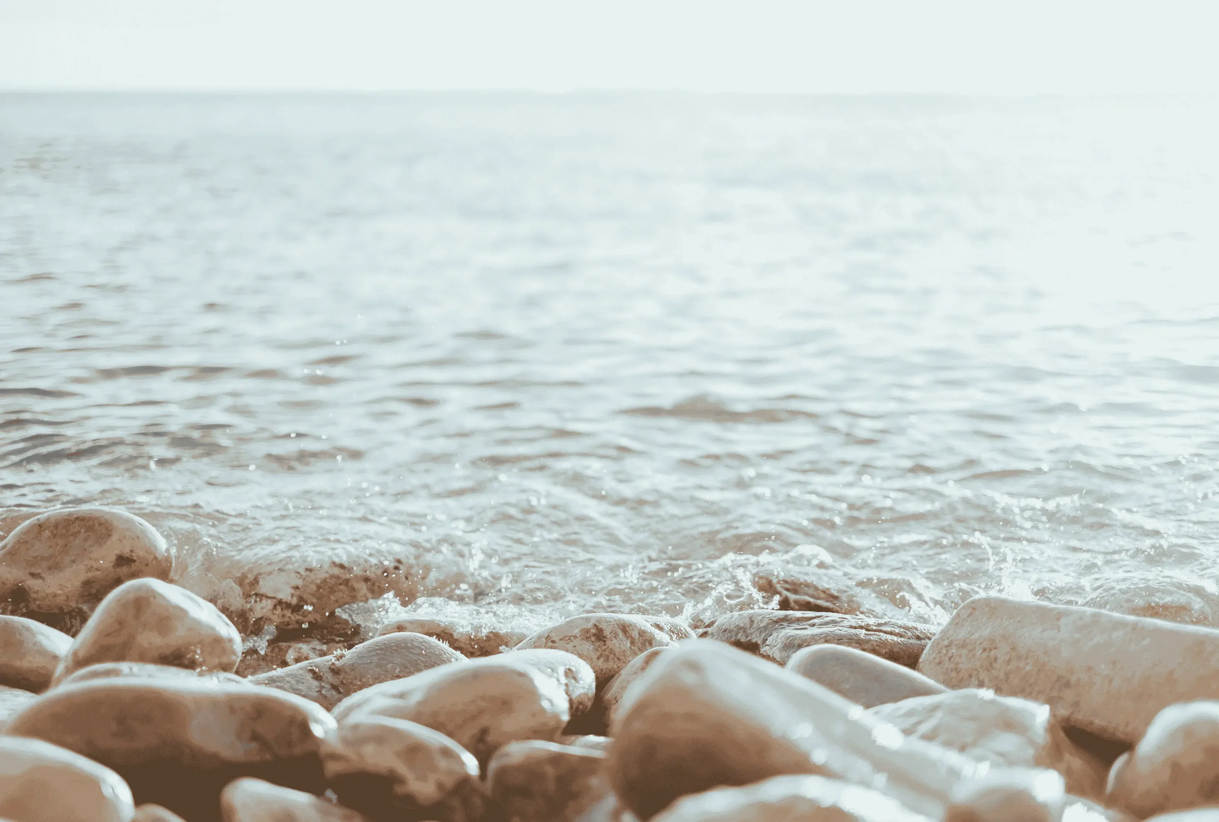 A smooth stone overlooking calm, quiet water, reflecting mindfulness and peace.