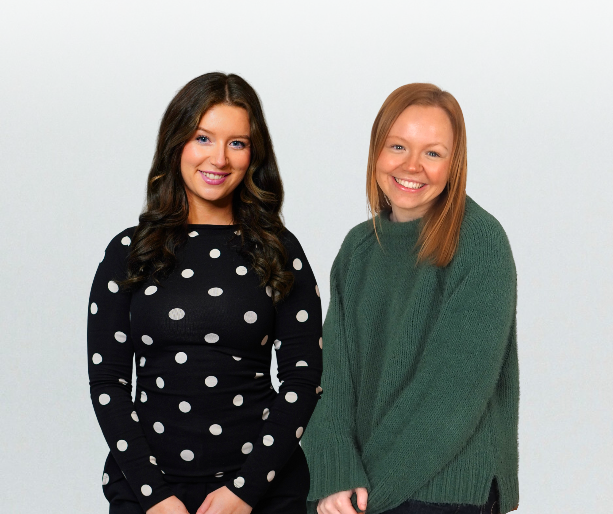 Two smiling women standing side by side against a plain white background.