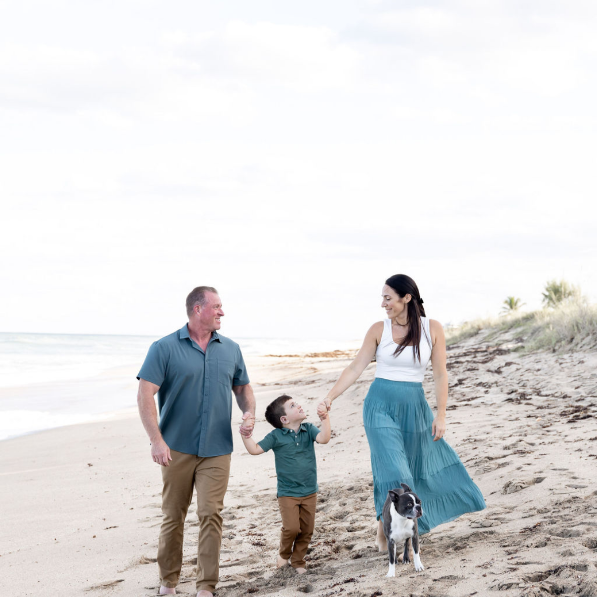 Family walking on the beach with their dog.