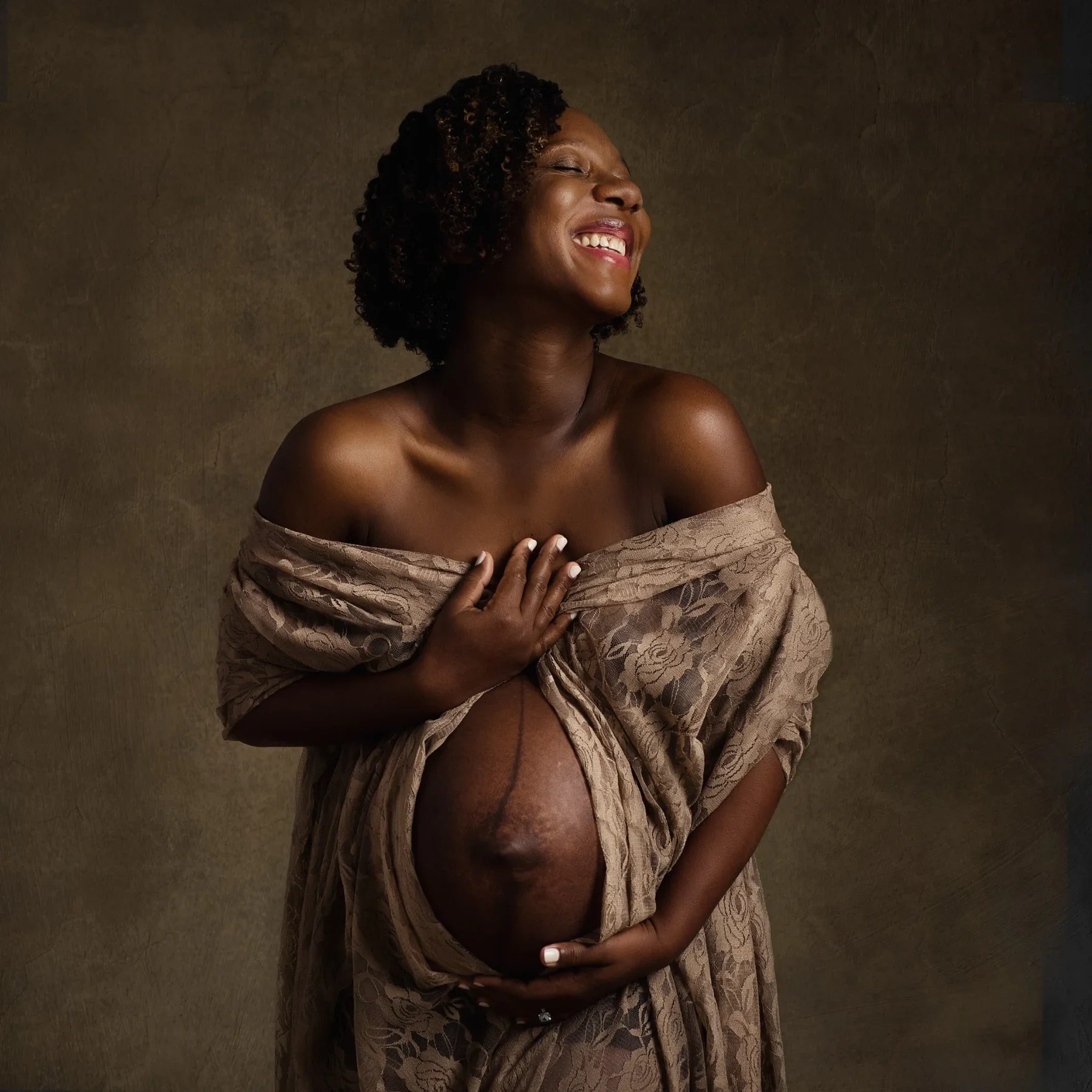 An expectant mother laughing with her hand resting over her heart