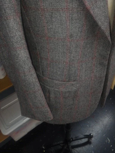 Close-up of a gray plaid blazer  with a small pocket.