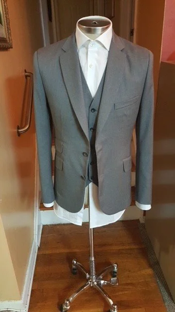 Gray suit jacket and vest worn over a white dress shirt.