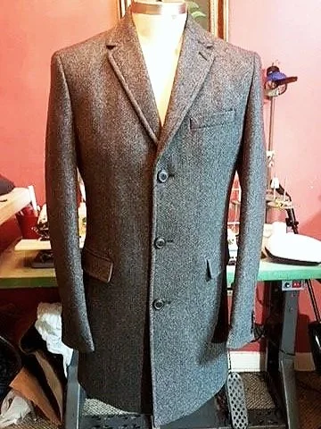 Gray tailored overcoat with a notched lapel and button closures.