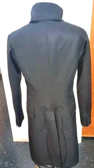  Long black coatwith a high collar and a belt around the waist.