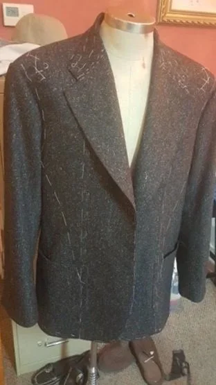 Close-up of a dark gray suit jacket  with visible markings and patterns on the fabric 