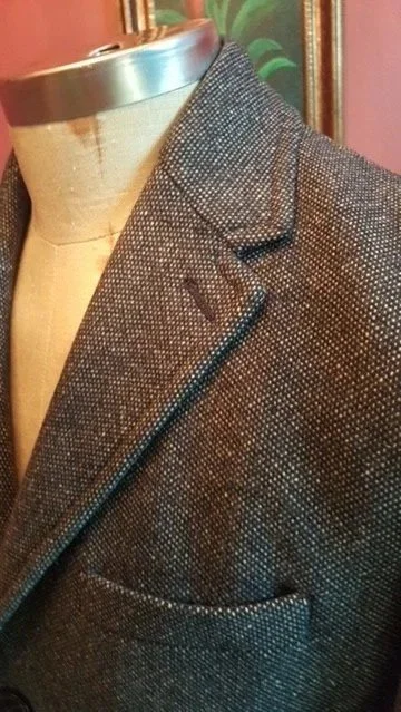 Close-up of a textured blazer with a lapel and pocket visible.