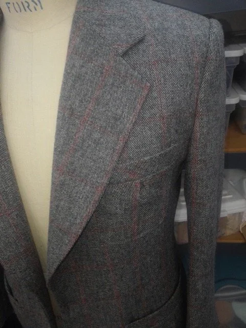 Close-up of a gray blazer with red and black check pattern.