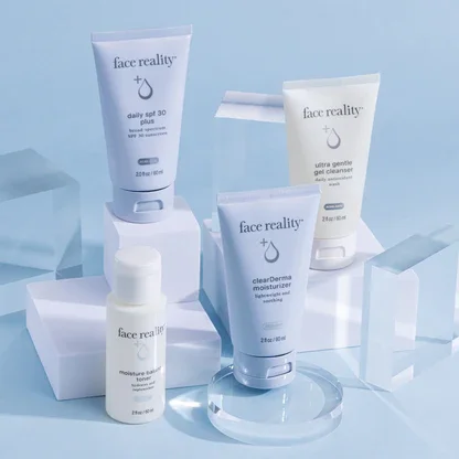 Collection of skin care products from Face Reality, including daily SPF 30, gentle cleanser, moisturizer, and another product, arranged on clear acrylic blocks against a light blue background.