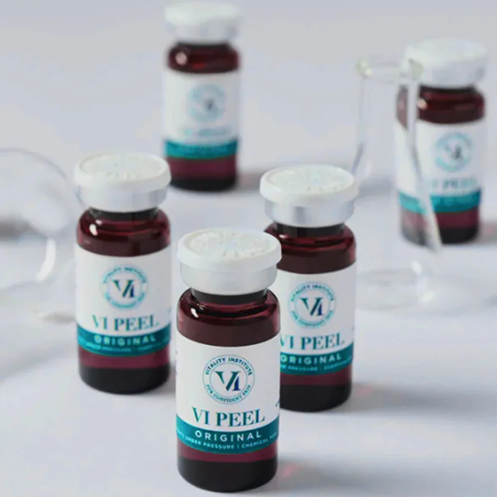 Multiple small bottles labeled 'VI Peel Original' on a white surface with some bottles in the background and open caps placed nearby.