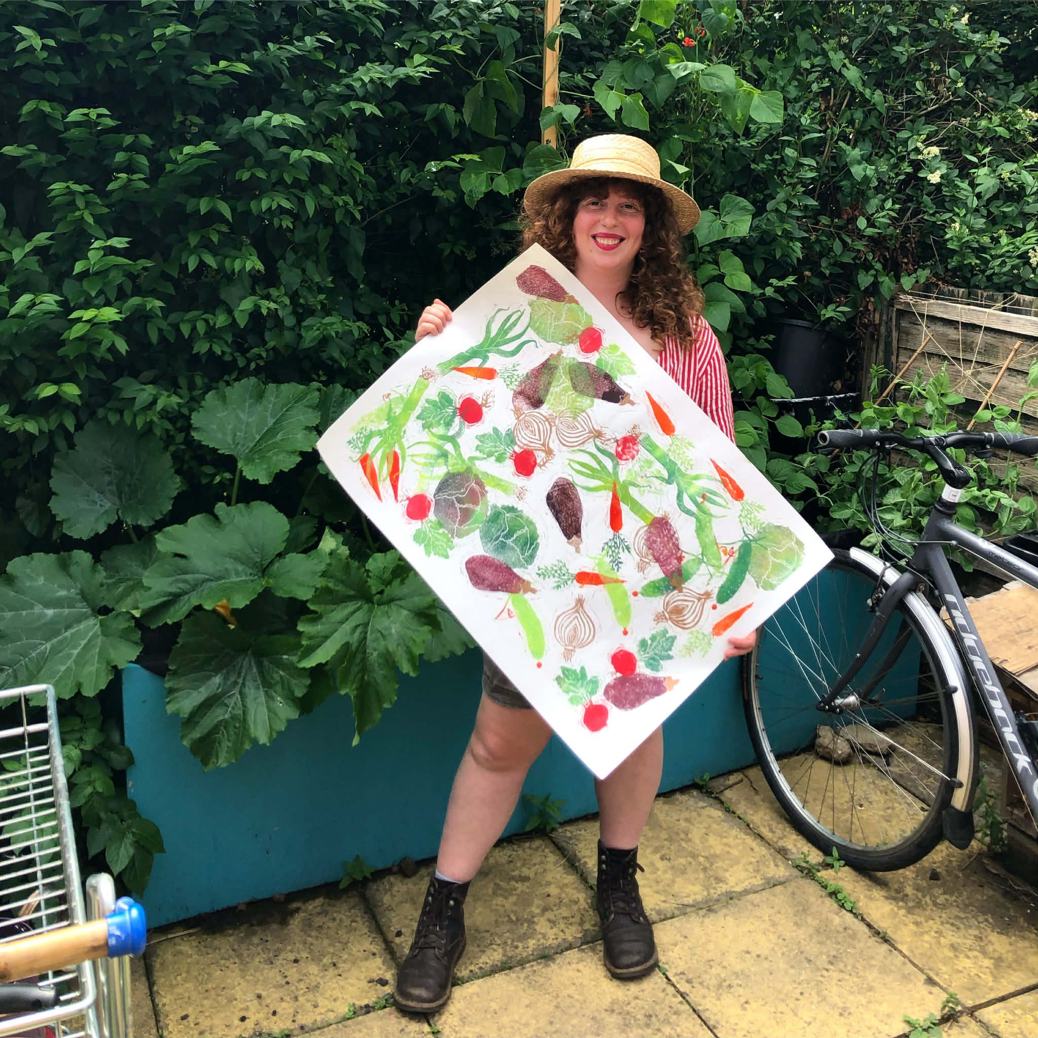 Emily in the garden holding a print of vegetables