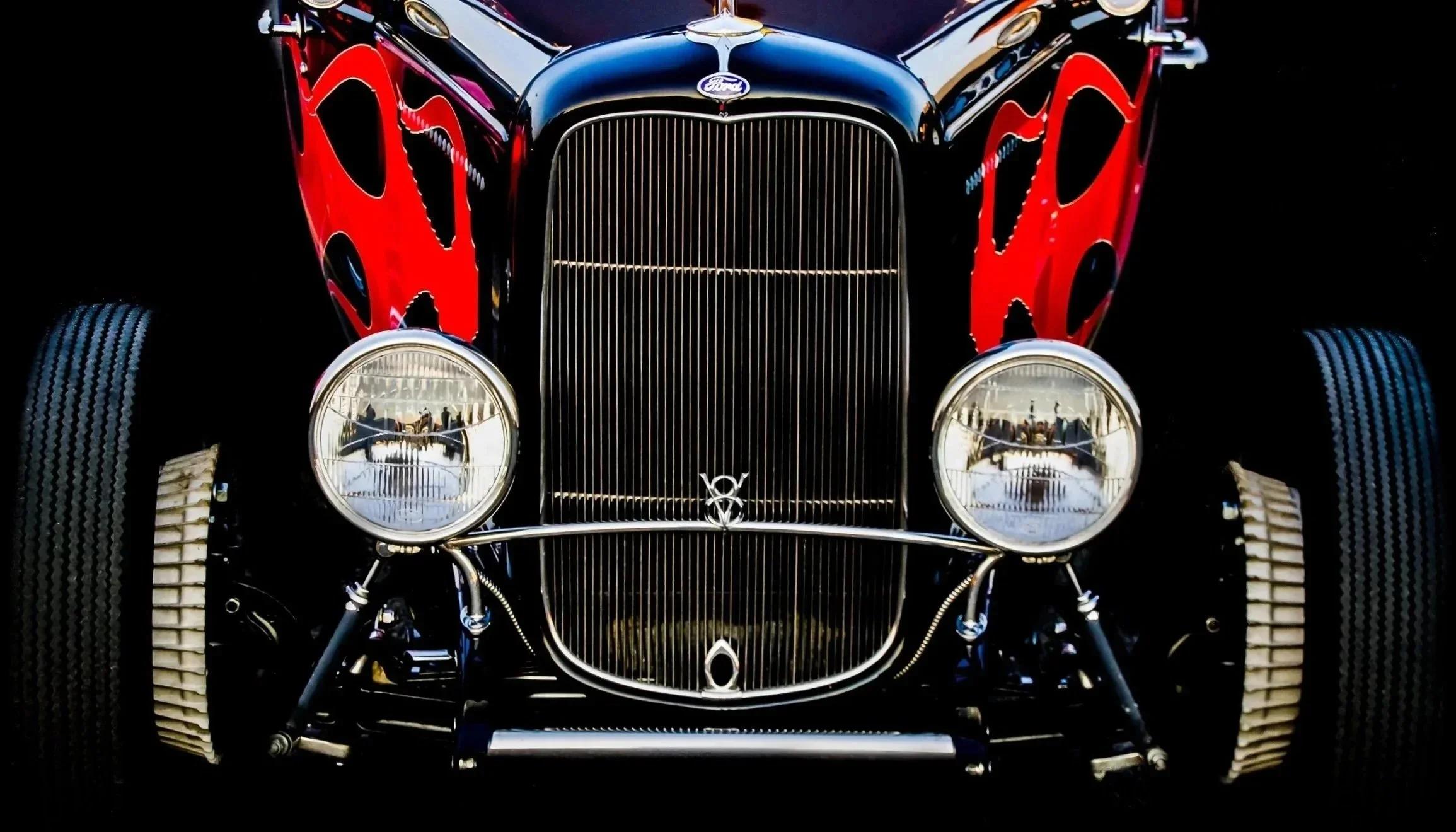 Front view of a vintage black and red Ford car showing the grille, headlights, and tires. Car with characater. Polka dots finish.