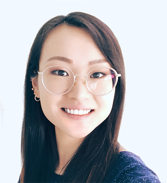 Close-up of a young woman with long dark hair wearing glasses and smiling at the camera.
