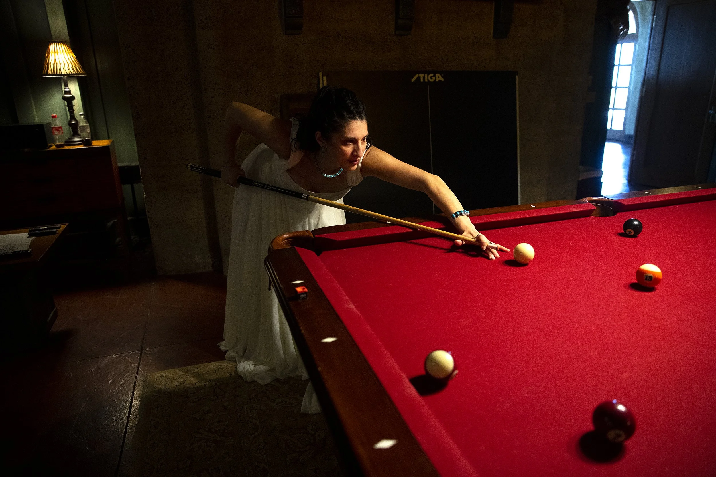 A bride plays pool while taking pictures before her wedding ceremony at the Little Daisy in Jerome, Arizona. Photographed by Megan Farmer, a documentary style wedding photographer based in Seattle, Washington. 