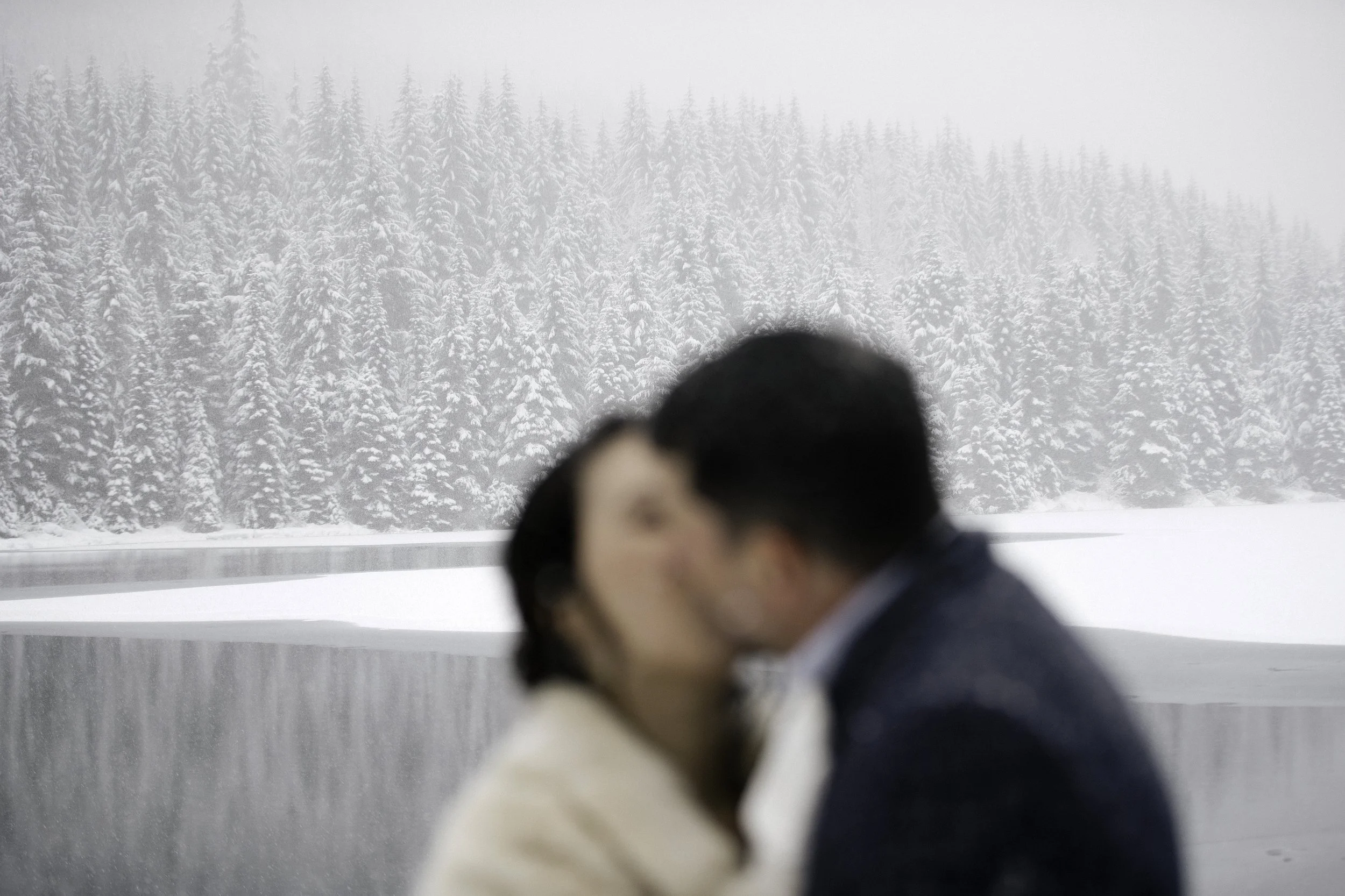 A bride and groom share a kiss in a snowy landscape at Golden Creek Pond in Snoqualmie Pass, Washington, following their wedding ceremony, photographed by documentary style wedding photographer Megan Farmer, based in Seattle, Washington. 