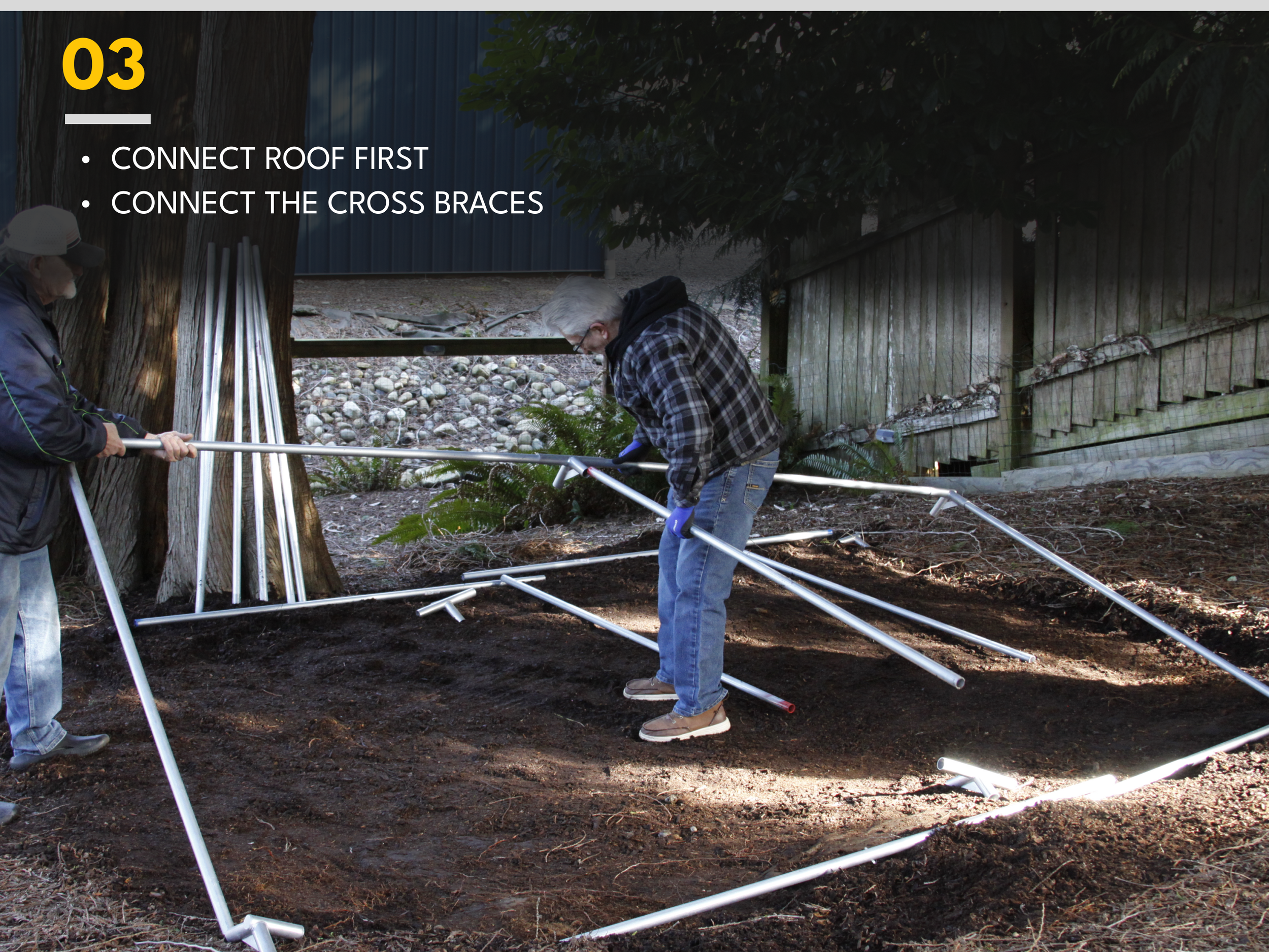 Two people assembling a metal structure or frame on dirt ground outdoors, near a tree and a wooden fence, with instructions to connect the roof first and connect the cross braces.