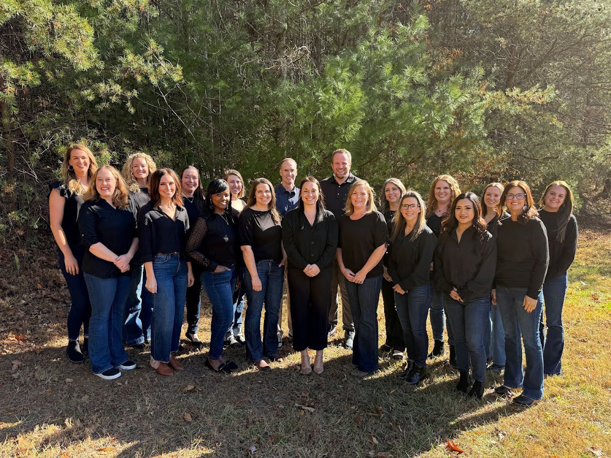 Parkview Dental's entire staff standing outside on a lawn in a group smiling in front of green trees