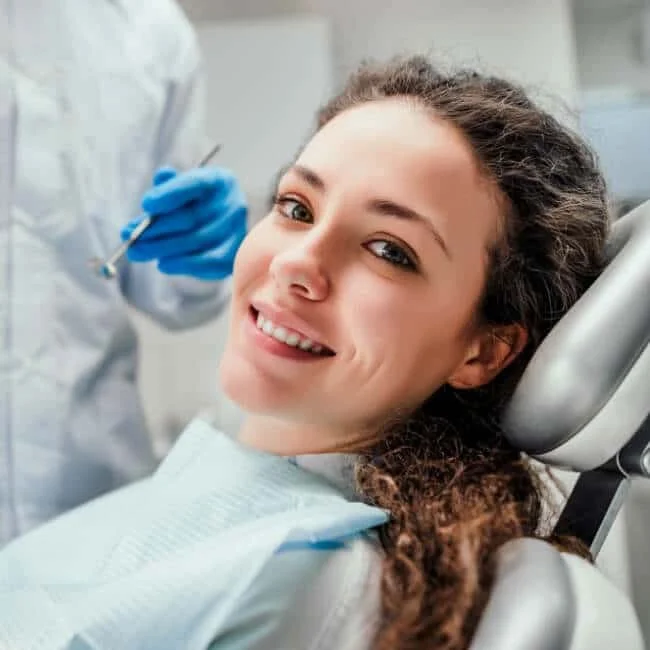 Woman smiling at the camera while sitting in a dentist chair