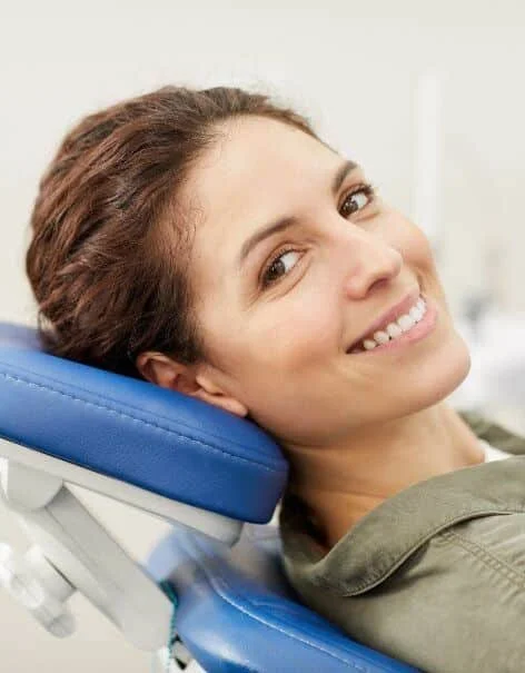 Woman smiling at the camera while resting her head back in a dentist chair