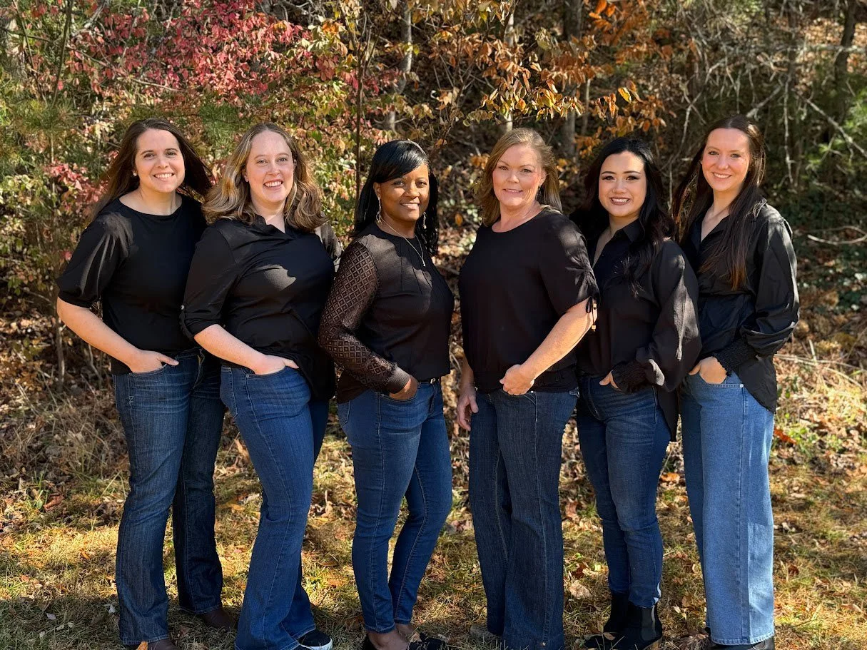 Parkview Dental's dental assistant team of 6 women standing outside together with their hands in their pockets smiling