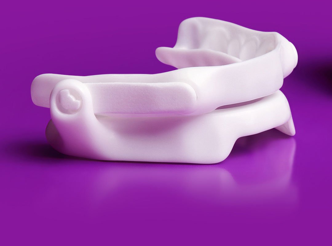 Dental appliance for sleep apnea on a purple surface