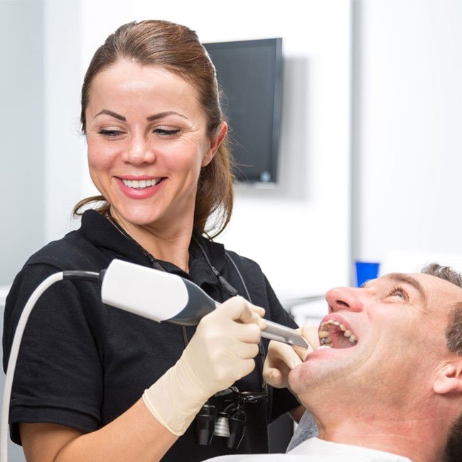 Dentist smiling while performing a dental crown procedure on a patient.