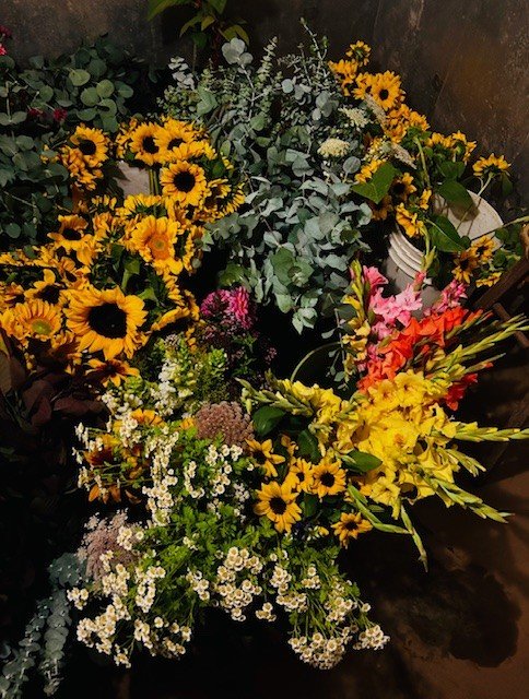 Abundant bunches of cut sunflowers, gladiolus, eucalyptus, and mixed blooms gathered for market