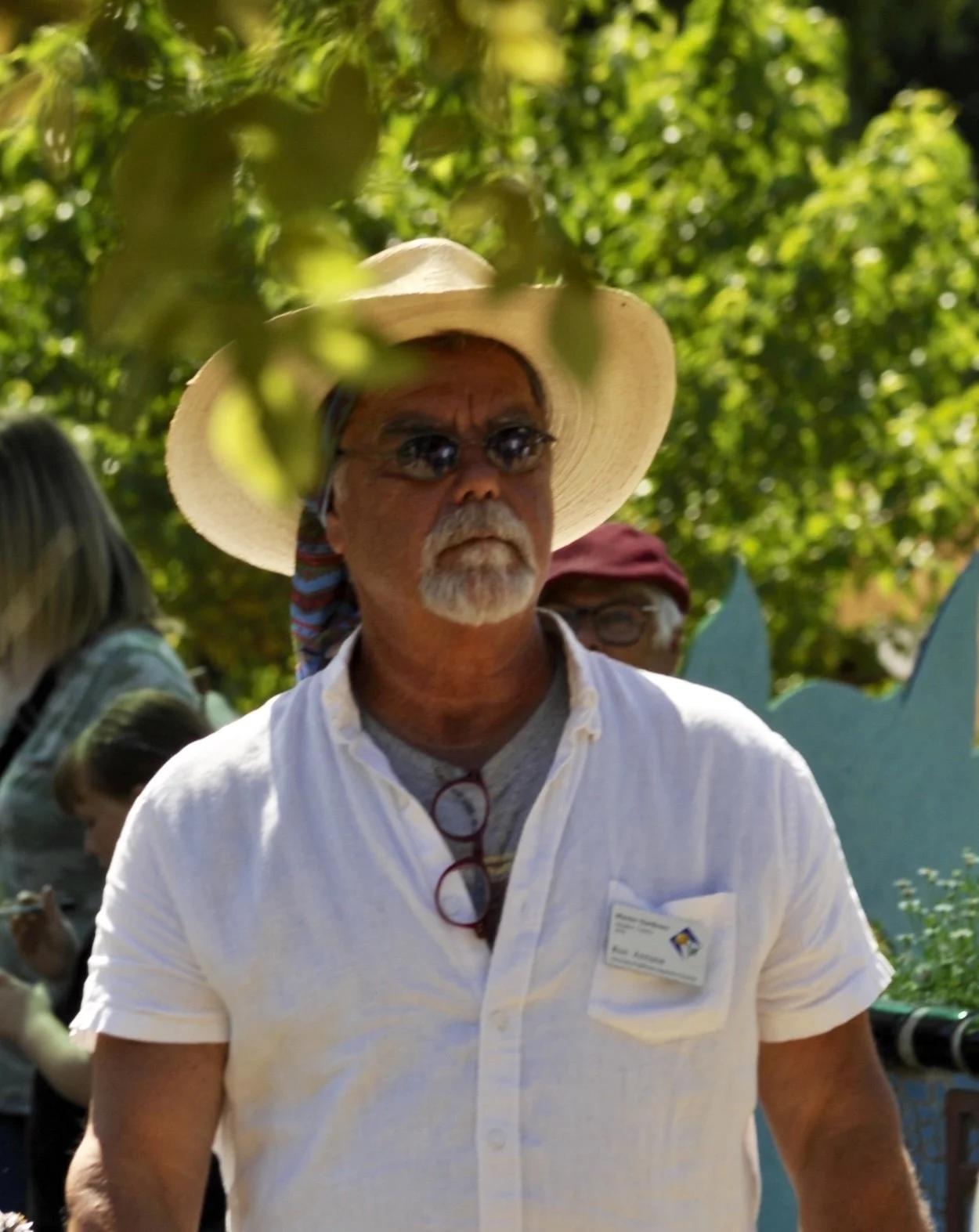 Ron, a bearded man in a straw hat and sunglasses, standing at an outdoor market