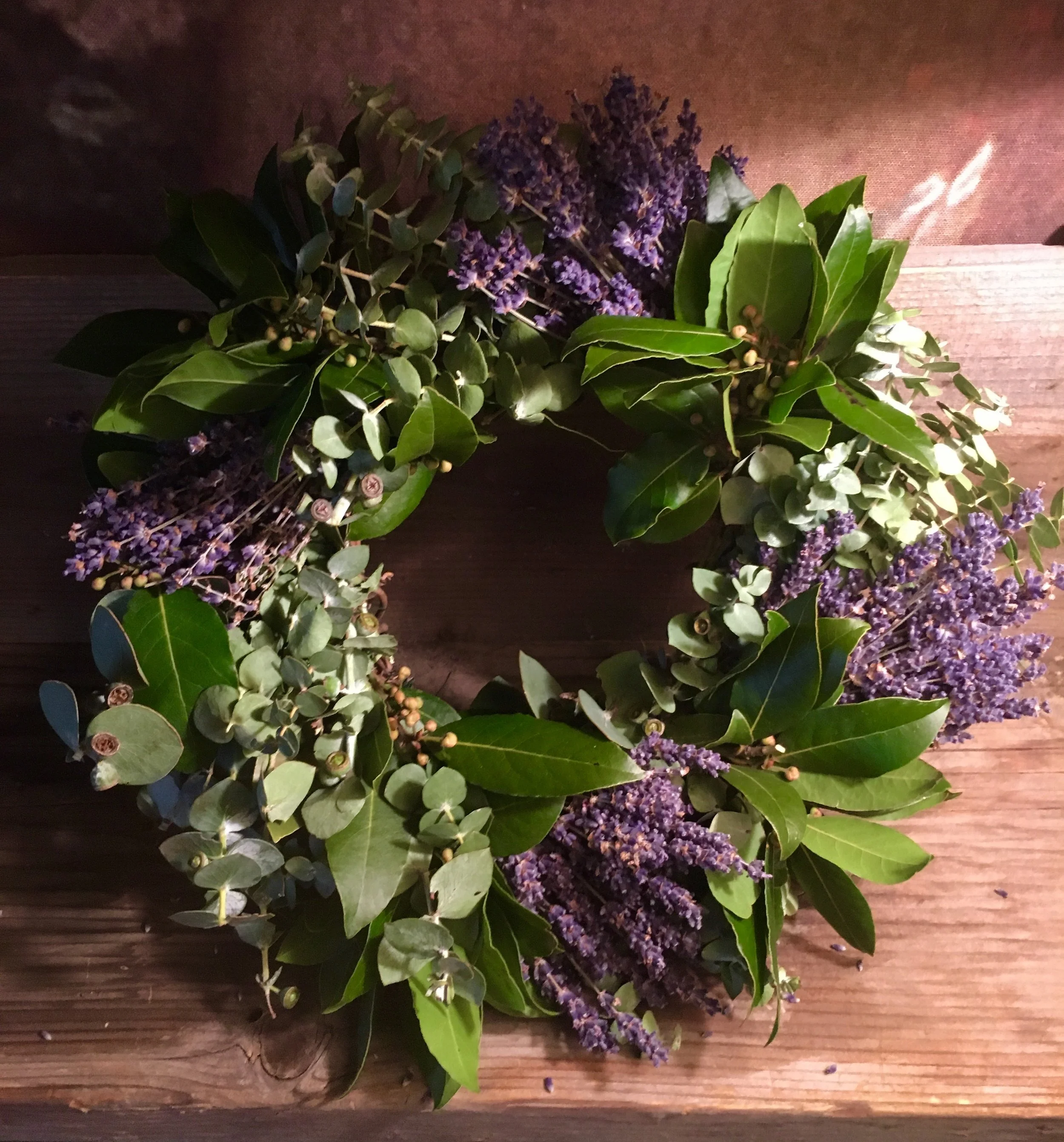 Handmade wreath of purple lavender, bay leaves, eucalyptus, and dried berries on wood