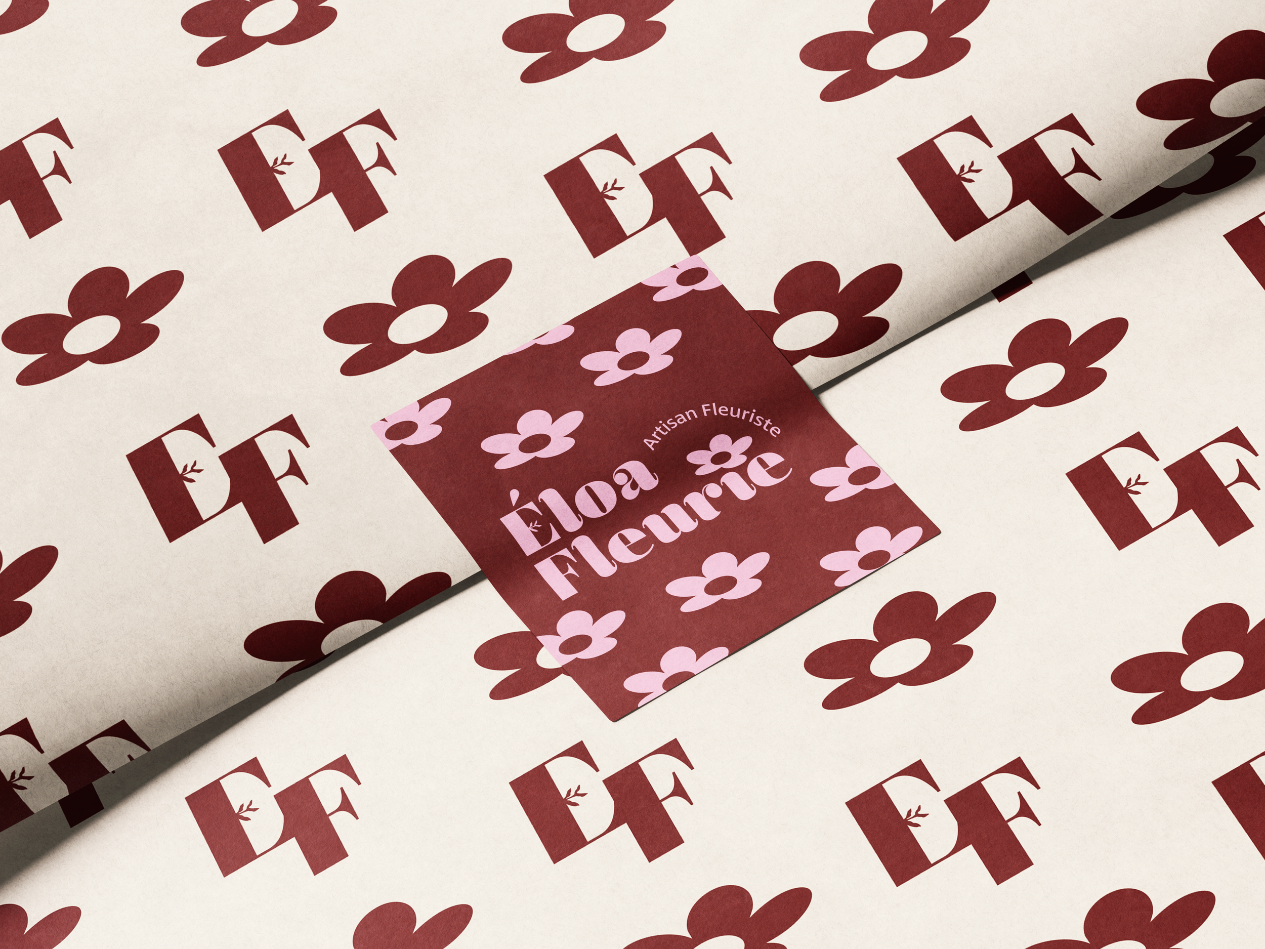 Une feuille de papier à motifs de fleurs rouge foncé et rose clair avec du texte en français "Fée Fleurie" et la mention "Artisan Fleuriste".