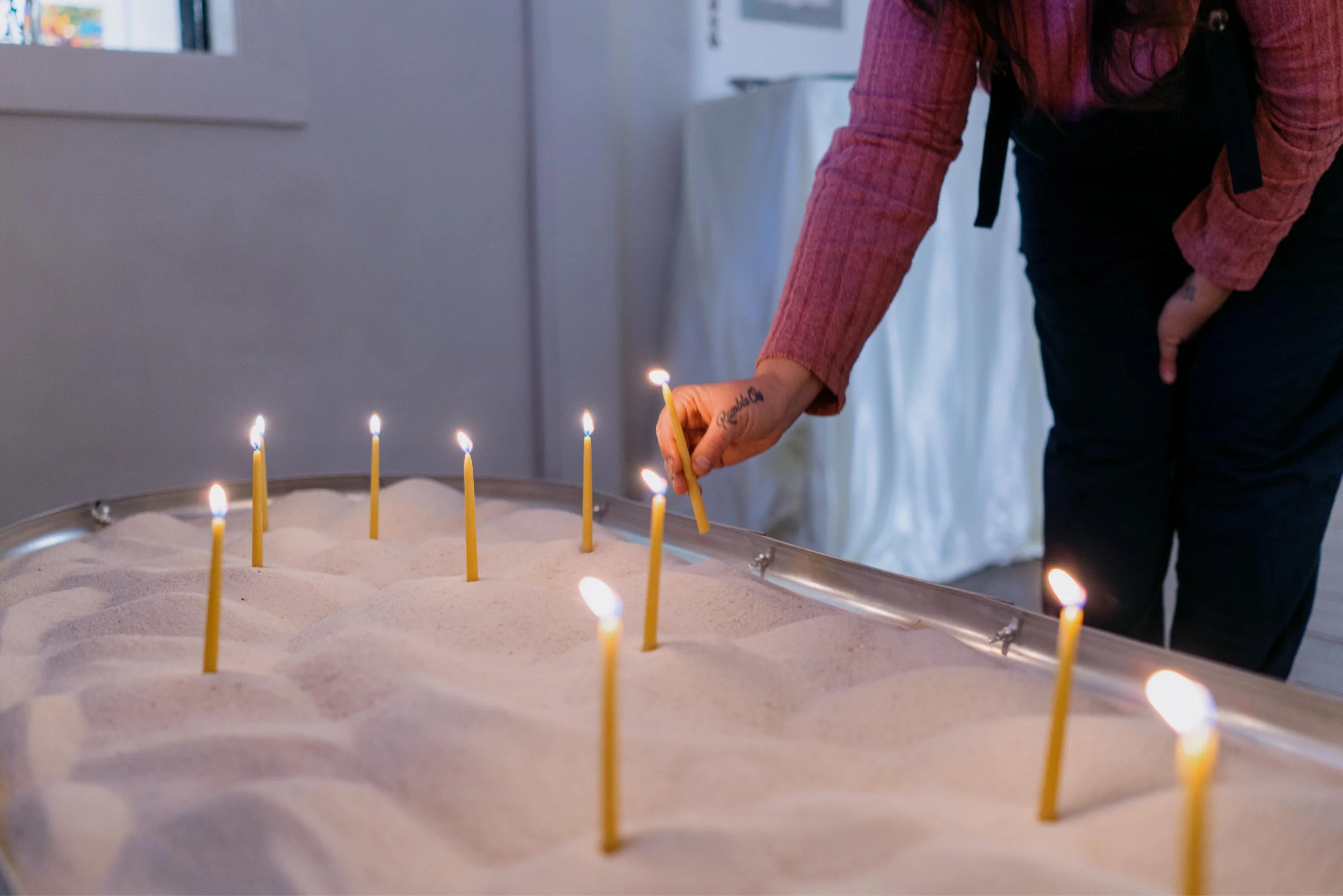Person placing candles onto a sculpture.