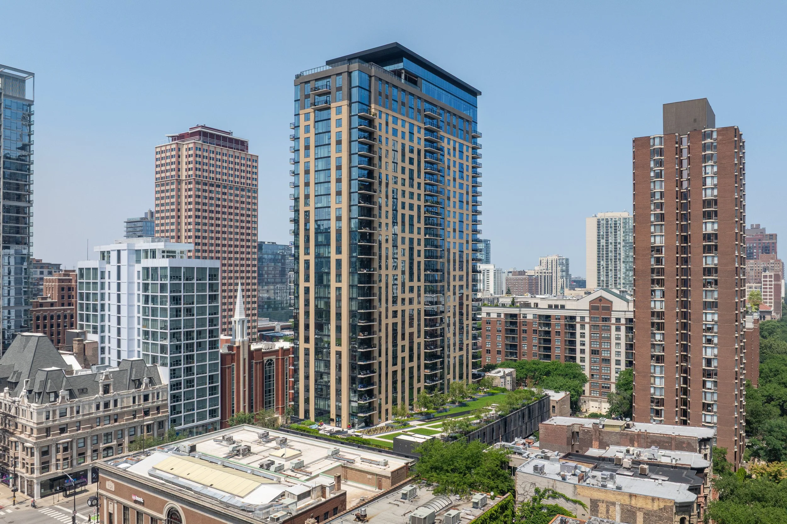 A cityscape showing modern high-rise buildings and skyscrapers under a clear blue sky.