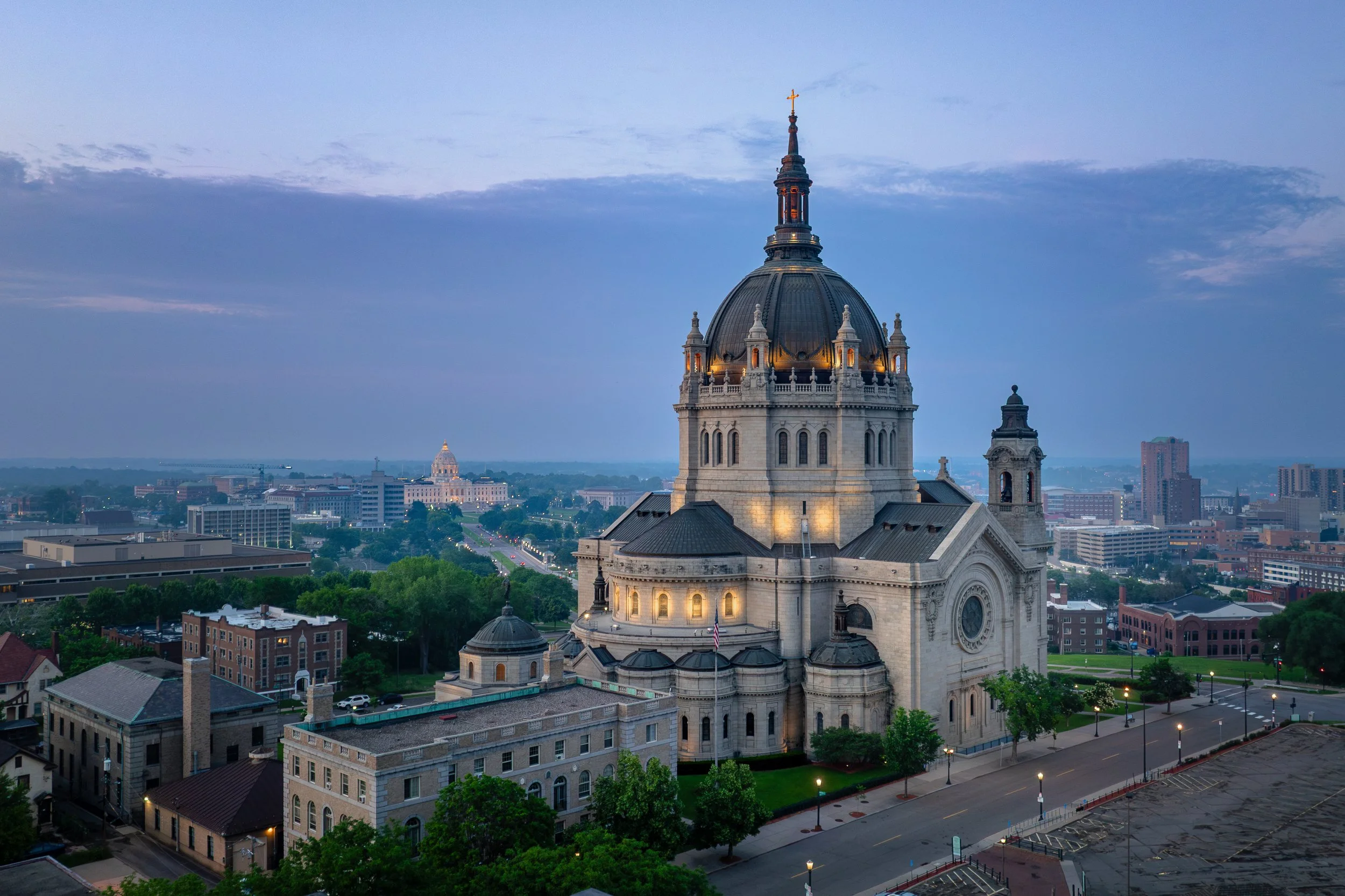 The domed Capitol building illuminated at dusk with cityscape in the background.