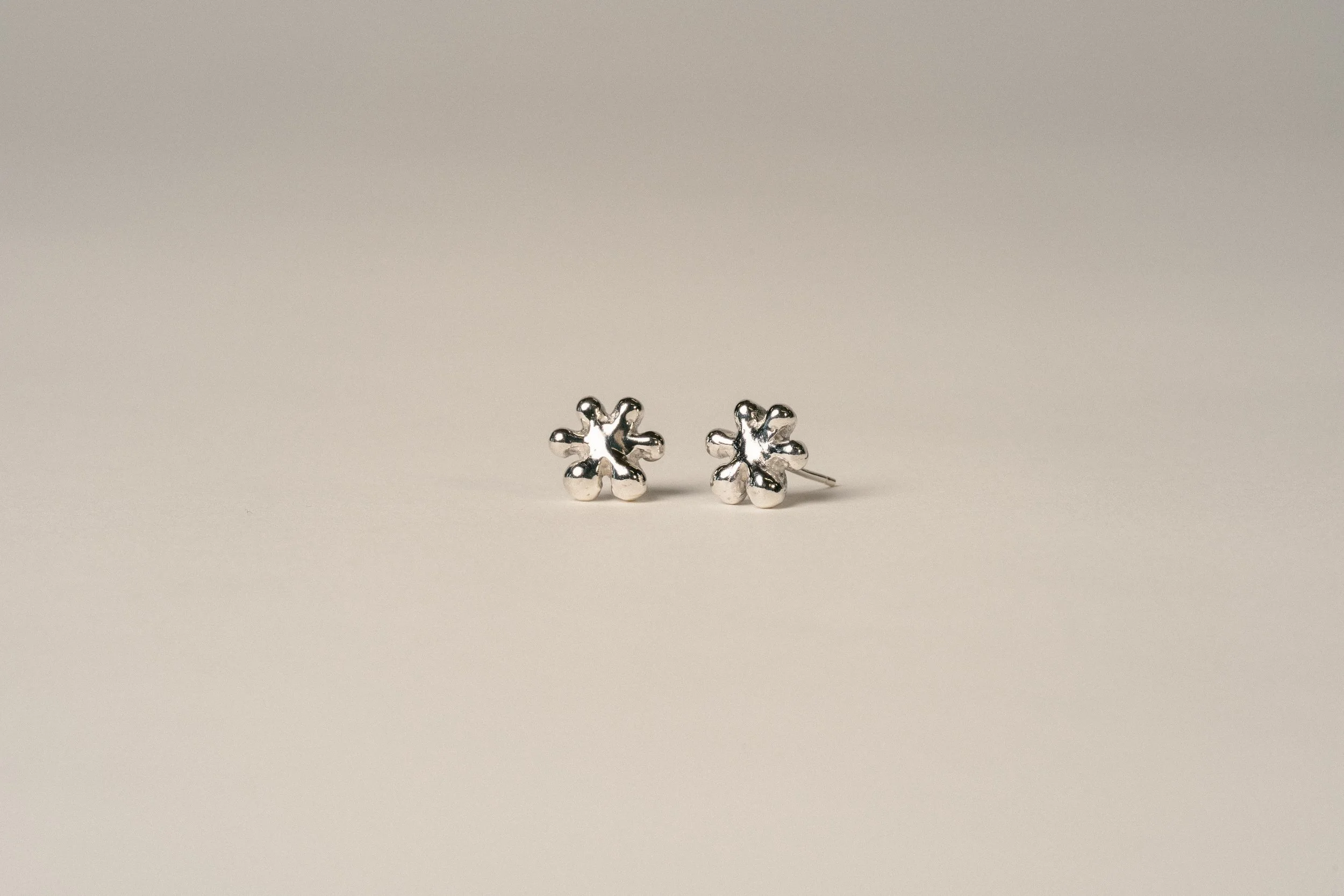 Silver flower-shaped stud earrings on a plain white background.
