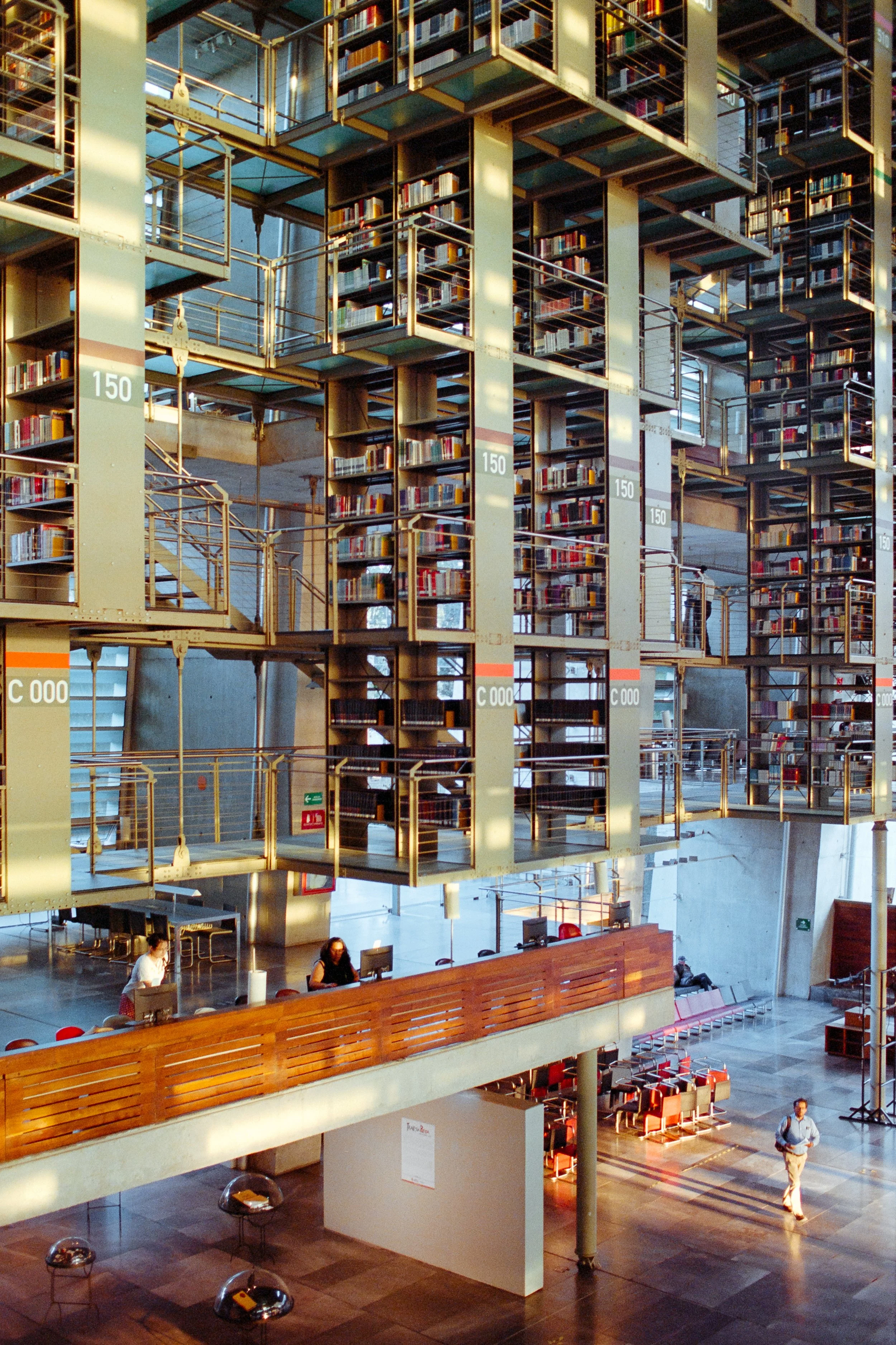 Interior of a modern library with multiple floors of bookshelves, open space, and people working at desks.