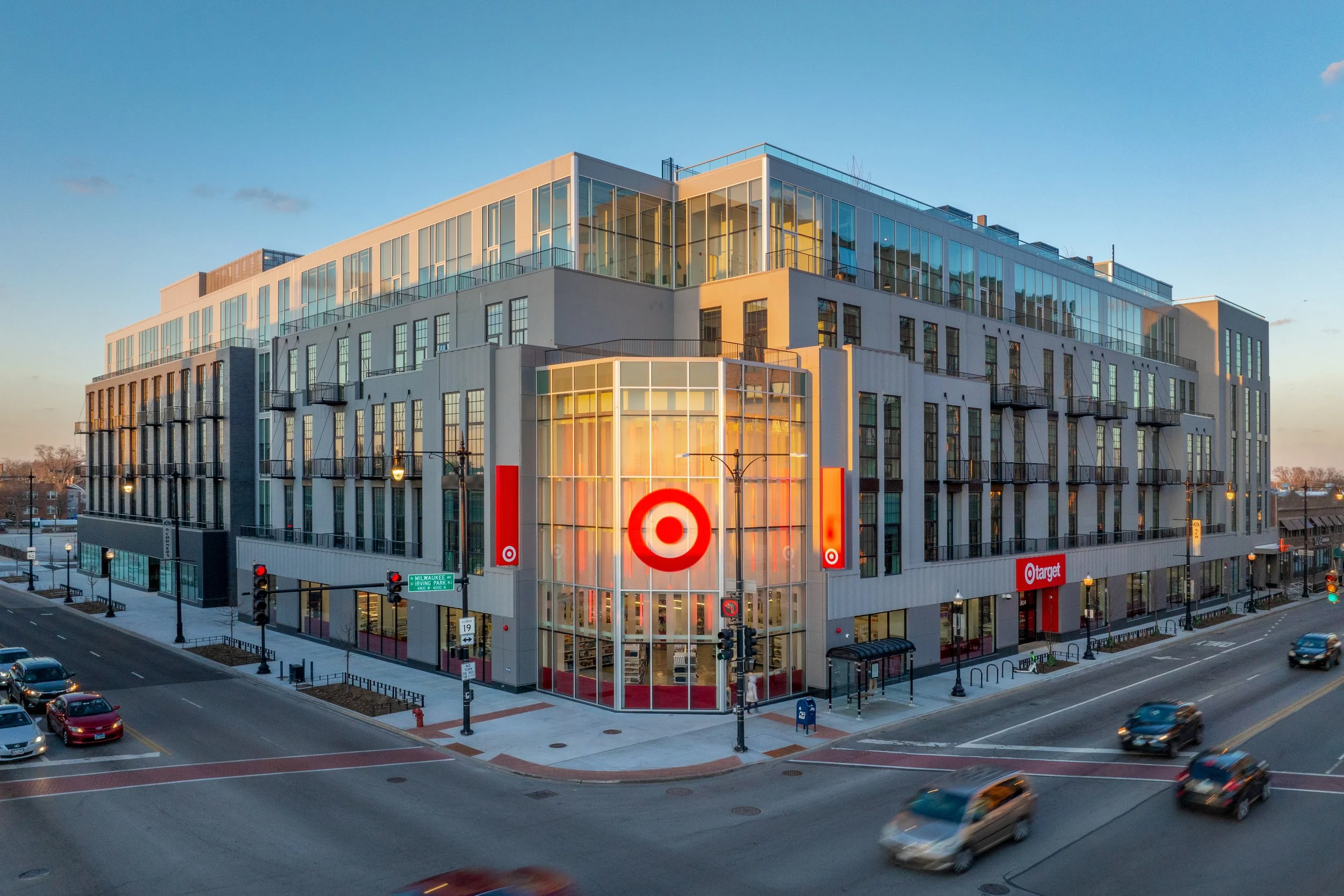 A modern multi-story Target store located at a city street corner during dusk with cars passing by.