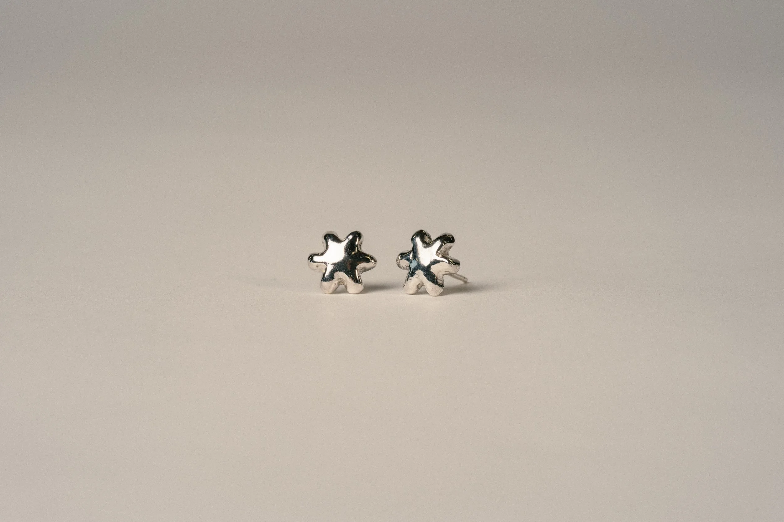 Silver star-shaped stud earrings on a plain, light-colored surface.