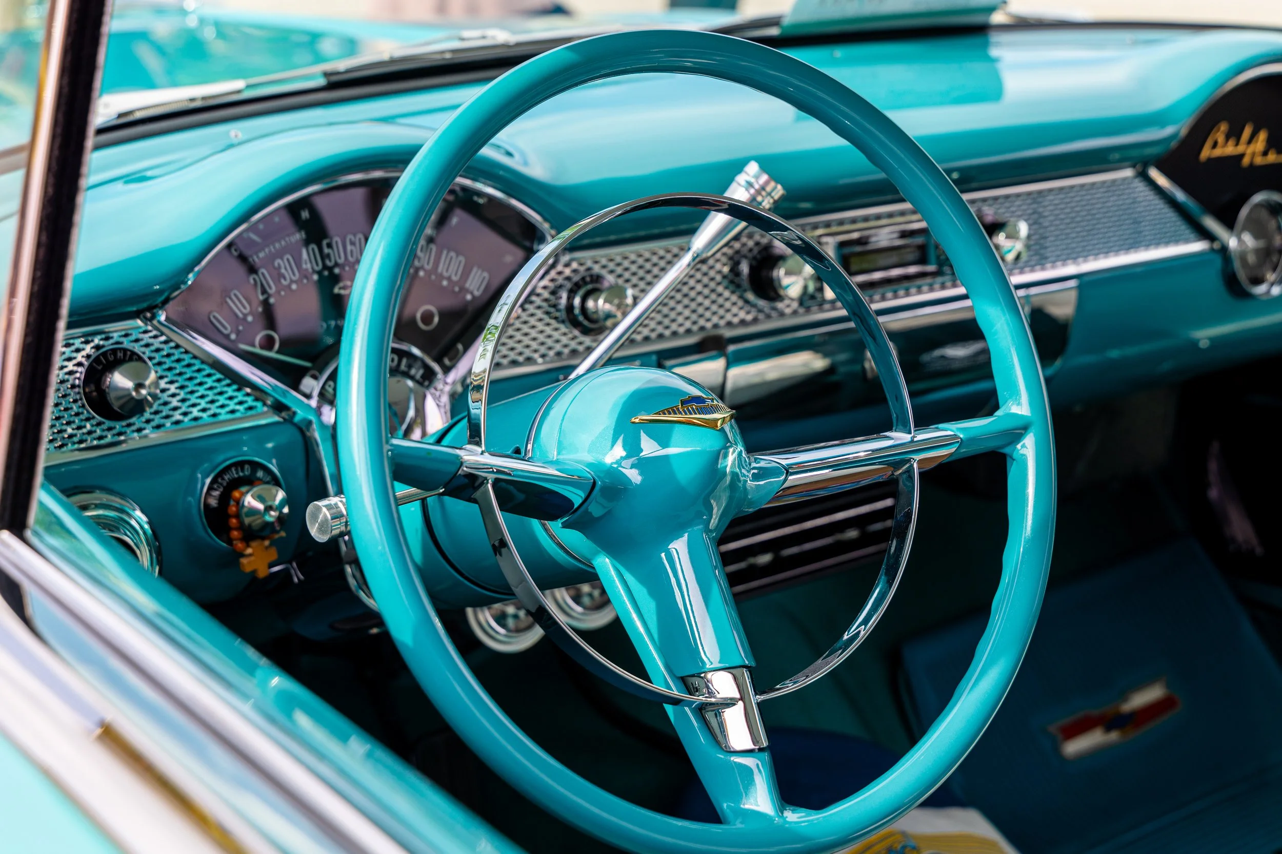 Interior view of a vintage Chevrolet car showing a bright blue steering wheel, dashboard, and speedometer.
