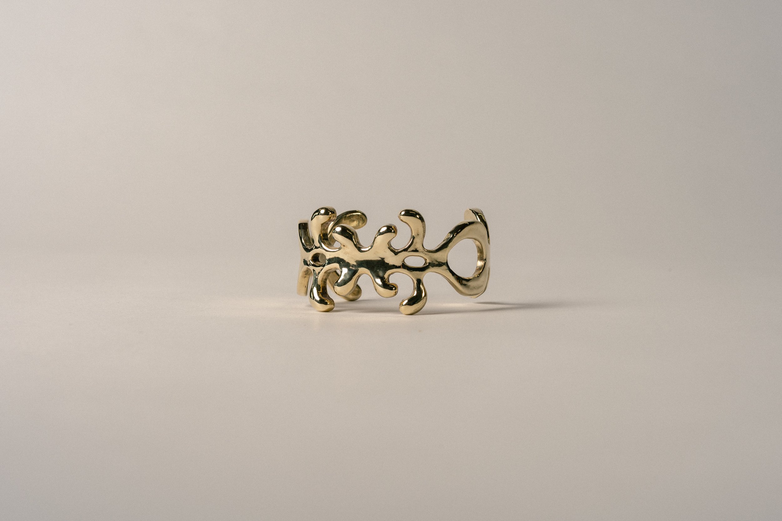 Gold abstract sculpture resembling coral isolated on a white background.