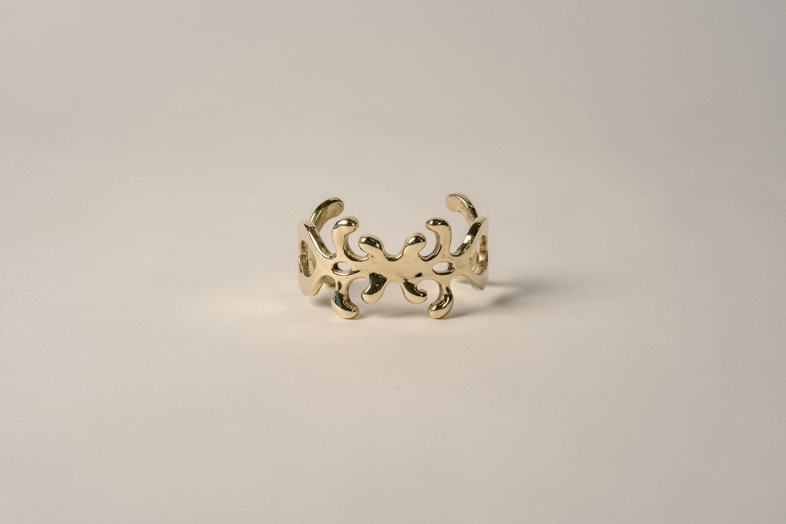 Gold ring with an intricate, abstract design on a plain background.