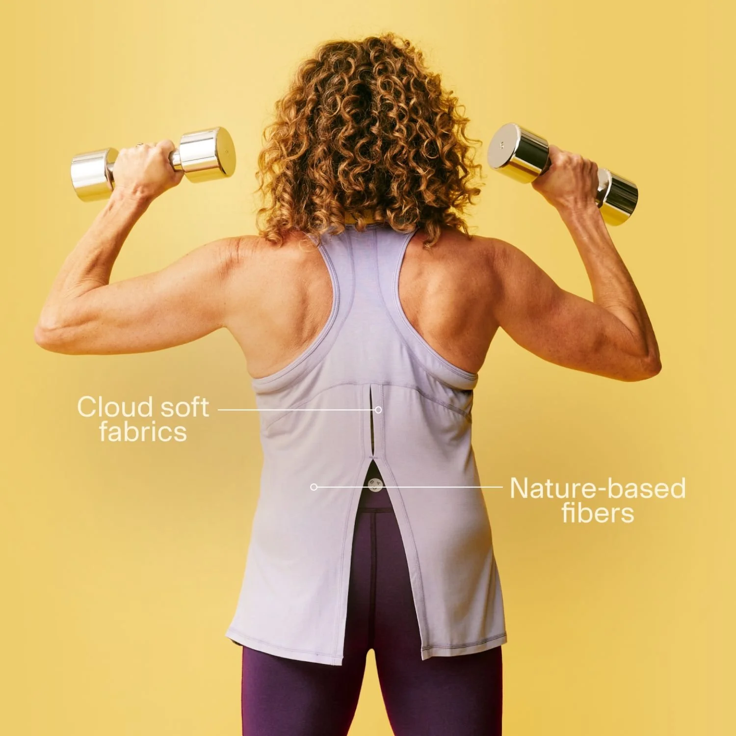 Sally Gunnell exercising against a yellow background, lifting dumbbells. 
